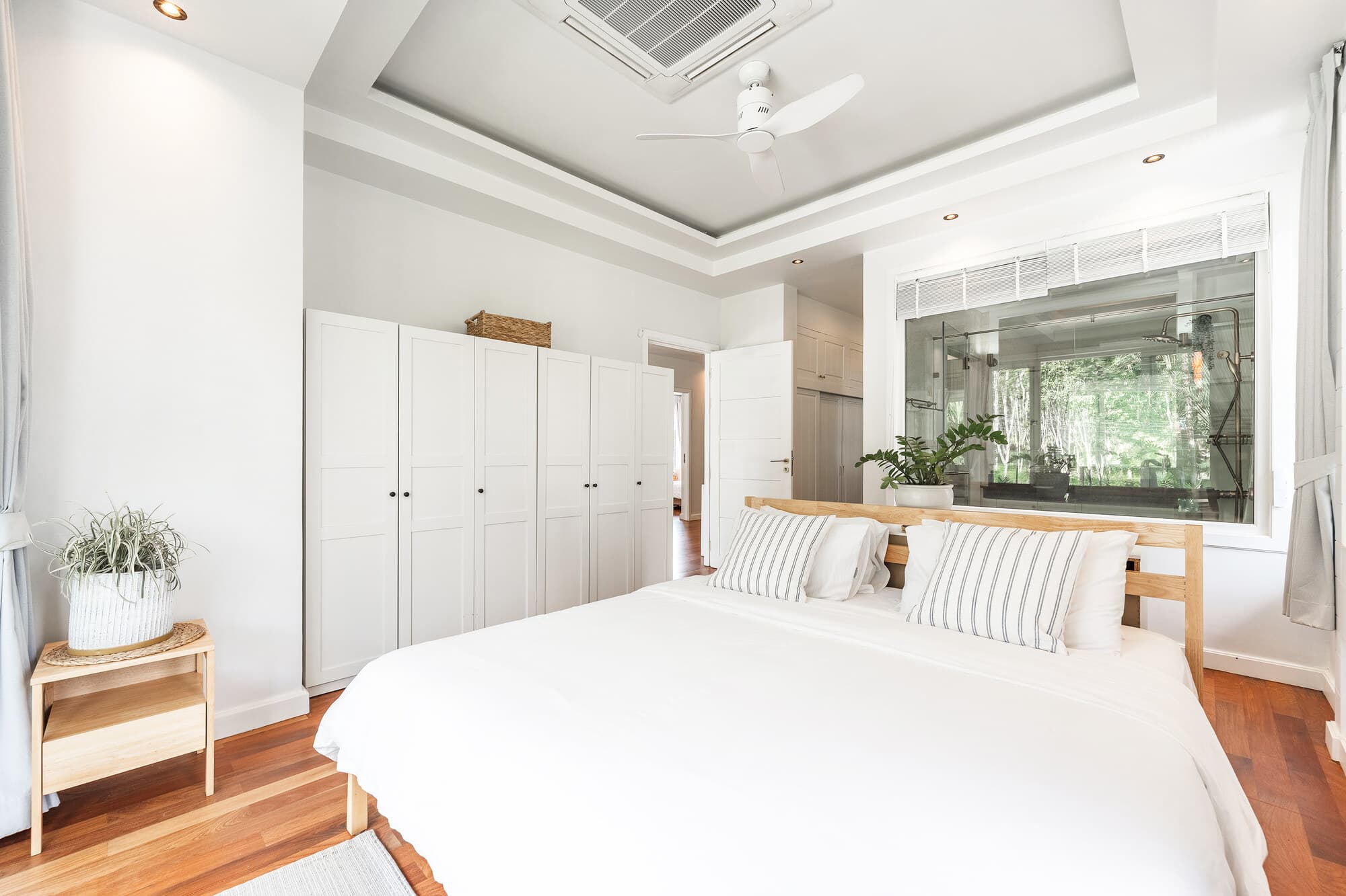 ห้องนอนหลักสว่างพร้อมตู้สีขาวและหน้าต่างห้องน้ำ ensuite